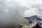 Harsh mountain landscape hiding behind cumulus clouds