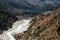 Harsh mountain landscape with a rocky bottom of the valley and a glacial river.