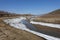 Harsh natural landscape and road along the riverbed and mountains for off-road SUV with puddles of snow and mud. Spring background