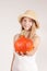 Harvest girl with hat is offering pumpkin