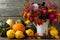Harvest pumpkins and a bouquet of autumn flowers on a wooden background