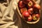 Harvest in a straw basket with many red ripe apples on draperied bedcover.