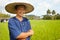 Almost harvest time. Portrait of a rice farmer holding a traditional harvesting tool - Thailand.