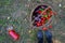 Harvest of tomatoes, hot red green peppers and eggplants in a basket, next to the grass is tomato juice in a bottle. Farmer`s feet