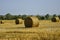 Harvested field with large round bales of straw in summer. Farmland with blue sky. Copy space. Close-up.