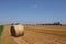 Harvested field with several rolled hay bales in Summer