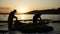 Harvested seaweed being rinsed in the ocean water by farmers, with the sun setting on the horizon