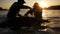 Harvested seaweed being rinsed in the ocean water by farmers, with the sun setting on the horizon