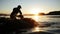 Harvested seaweed being rinsed in the ocean water by farmers, with the sun setting on the horizon