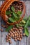 Harvested walnuts in a wicker basket on a wooden background. With and without leaves