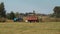 Harvester collects grass on the field with a tractor.