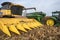 Harvester combine dumping corn into grain cart on back of tractor in corn field during harvest