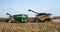 Harvester combine and grain cart on back of tractor