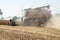 A harvester cutting dried, ripened soybeans stirs up a cloud of dust at harvest time.