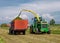 Harvester cutting field and loading into a Trailer