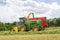 Harvester forager cutting field, loading Silage into a Tractor Trailer