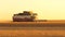 The harvester moves in field and mows ripe wheat. a large harvester harvests grain in the sunset. harvester mower