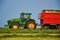 Harvester unloading into a tractor trailer. Combine harvester mows the field. Farming tractor collecting haystack. Slovakia