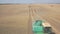 Harvesting grain with a few combines, in a large field.