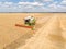 Harvesting of wheat in summer. Combine harvester agricultural machine collecting golden ripe wheat on the field. View