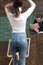 She has got the book she needs. Woman do hair in classroom rear view. Girl student hold book in legs stand in front of