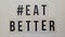 Hashtag # Eat Better with black letters on beige wooden background, logo design
