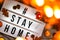 Hashtag Stay home. Text in white light box, with a background of sweater, candles, dried leaves autumn decoration. Coronavirus