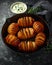 Hasselback baked potatoes served in cast-iron pan with sour cream salt, pepper and herbs
