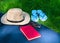 Hat, book sunglasses, flip flops on green grass in the park. Summer holiday concept.