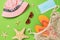 Hat, sunglasses, beach slippers, bag, medical mask and starfish on a green background, top view