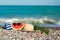 A hat, sunglasses, a sun cream and a towel is laying on a stony beach.