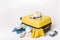 Hat and sunglasses on a yellow suitcase with clothes of the traveler on a white background. Travel and adventure concept