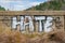 `Hate` graffiti painted on cement wall in large white capital letters.
