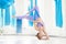 Hatha aero fly yoga concept. Beautiful young female trainer showing stretching exercises on blue hammock in white studio