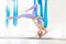 Hatha aero fly yoga concept. Beautiful young female trainer showing stretching exercises on blue hammock in white studio