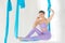 Hatha aero fly yoga concept. Beautiful young female trainer showing stretching exercises on blue hammock in white studio