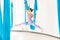 Hatha aero fly yoga concept. Beautiful young female trainer showing stretching exercises on blue hammock in white studio