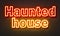Haunted house neon sign on brick wall background.