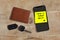 Have a great day romantic and sweet handwritten note on yellow posit stick to mobile phone next to car key and leather wallet in