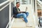 Have a lot of tasks to keep track Technology helps. a young businessman using a laptop on the stairs of a modern office.