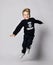 Having fun blond kid boy in black jersey sweater with printed words inscription jumps. Translation: `Want. Can. Will Do`