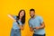 Having fun. Playful arab couple playing video games together, holding and using joysticks over yellow background