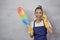 Having fun. Playful young woman in uniform holding colorful microfiber duster and kitchen sponge, pretending talking on