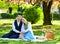 Having picnic in city park. man and woman relax with food basket. Romantic traveler couple under sakura blossom tree