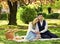 having picnic in city park. man and woman relax with food basket. Romantic traveler couple under sakura blossom tree