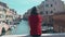 Having rest in the warm rays of the sun in Italy. Rear view of attractive brunette girl in red sweater sitting on edge