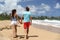 Hawaii couple walking on Kauai beach on summer travel vacation. Tourists people relaxing lifestyle in Kauai, Hawaii, USA