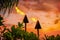 Hawaii luau party Maui fire tiki torches with open flames burning at sunset sky clouds at night. Hawaiian cultural travel vacation