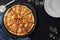 Hawaiian pizza with sweet pineapple and salty ham on dark stone background with plates, forks and glasses.