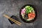 Hawaiian salmon fish poke bowl with rice, radish,cucumber, tomato, sesame seeds and seaweeds